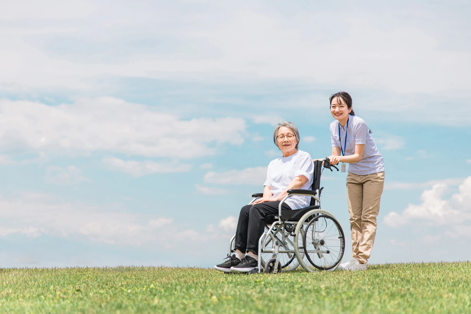 利用者さんの車いすを押す女性スタッフ