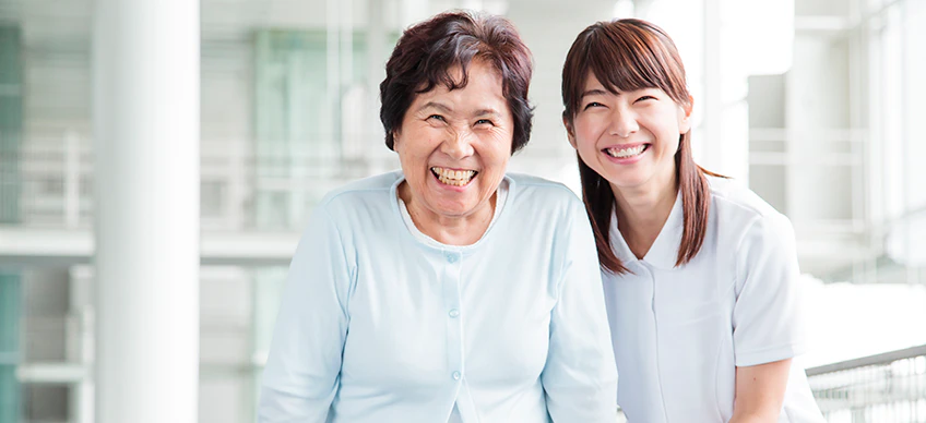 作業療法士の女性と患者さんが笑顔で並んでいる