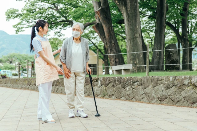 スタッフと杖をつきながら散歩する女性