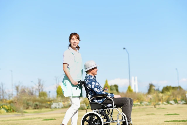 スタッフと外の散歩へ行く車椅子の男性