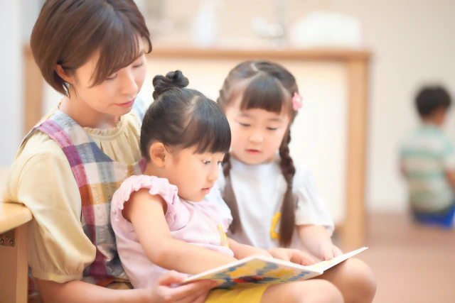 絵本を読む子供と保育士さん