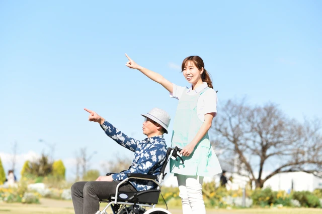 指をさす車椅子の男性と女性スタッフ