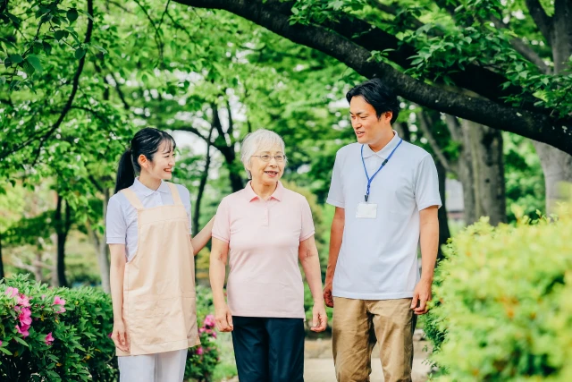 散歩する女性と支える男女スタッフ