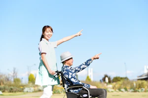 指をさす車椅子の男性とスタッフ