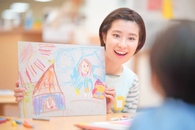 お絵描きをほめる保育士