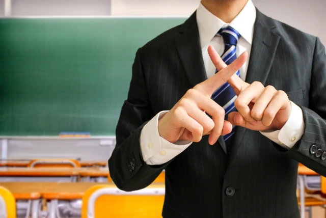 手でバツ印をする男性