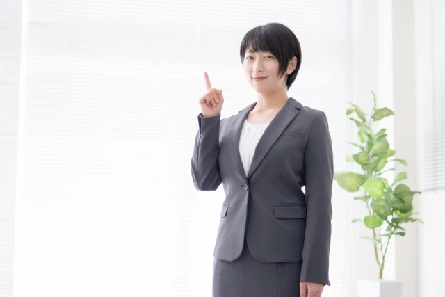 人差し指を上に向ける女性スタッフ