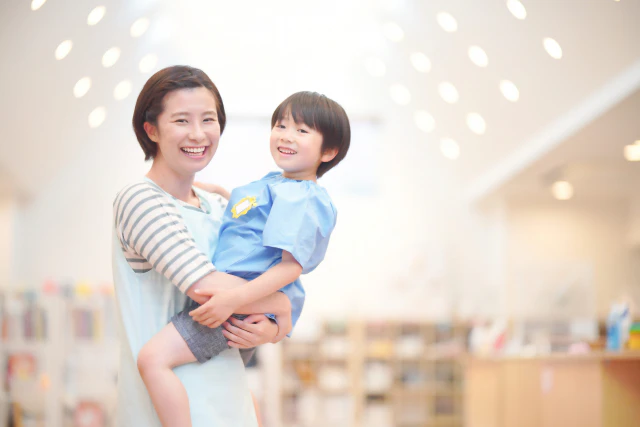 園児を抱っこする保育士