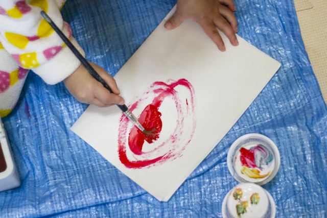 筆で絵を描く園児の手