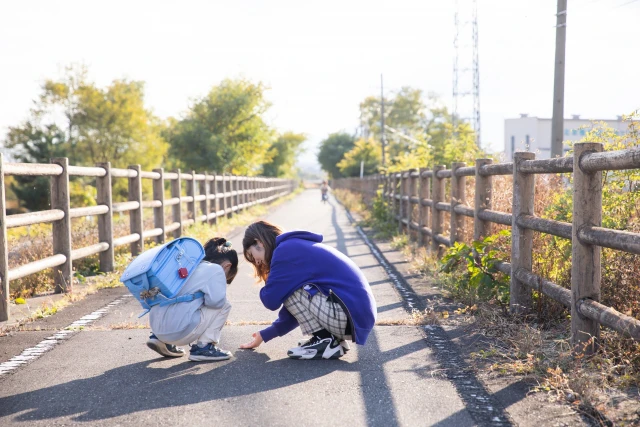 道端でしゃがみこんでいる女性と子供