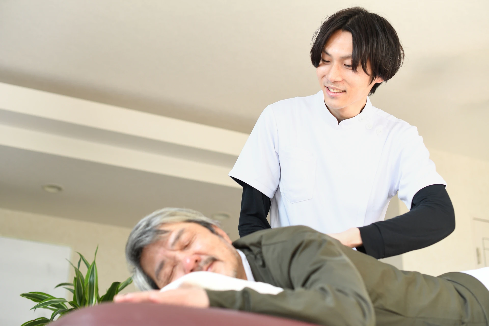 療法士さんに背中をさすってもらう男性
