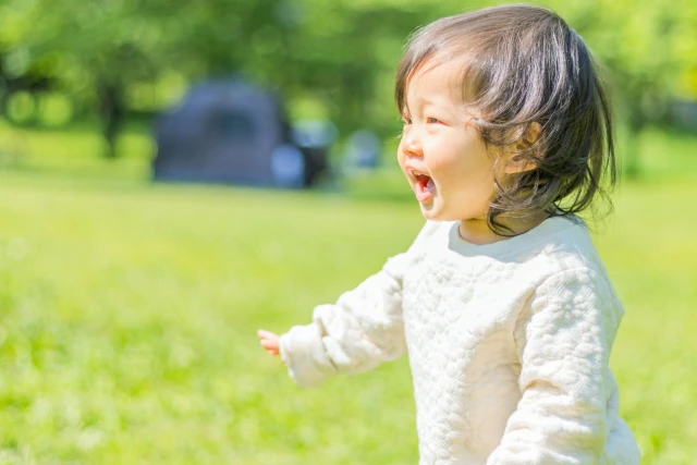 原っぱで笑顔を見せる女の子
