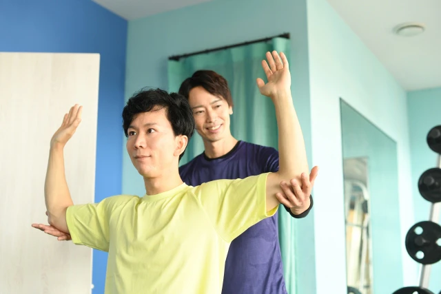手を挙げる男性とそれを支える男性