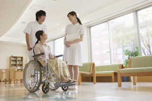 患者さんが乗った車いすを押す看護師