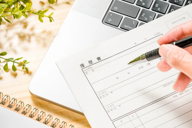 履歴書とペンを持つ手