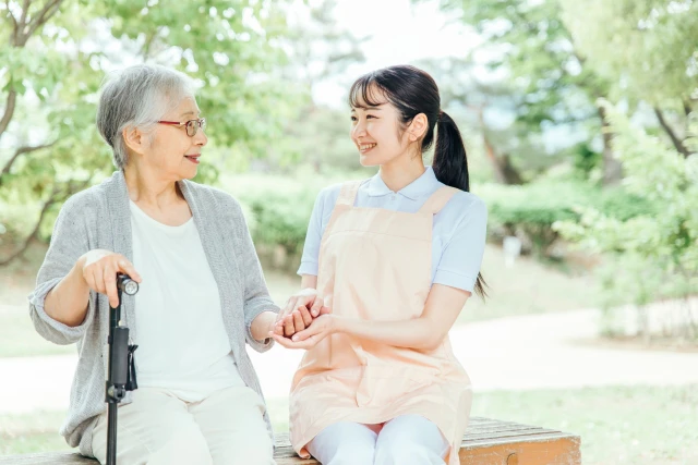 高齢者女性の手を握る理学療法士