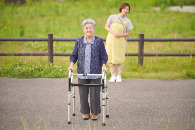 介護グッズを使用する女性と見守るスタッフ