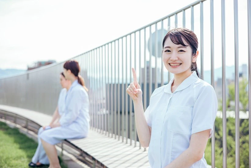 屋上で指さしながら微笑む女性