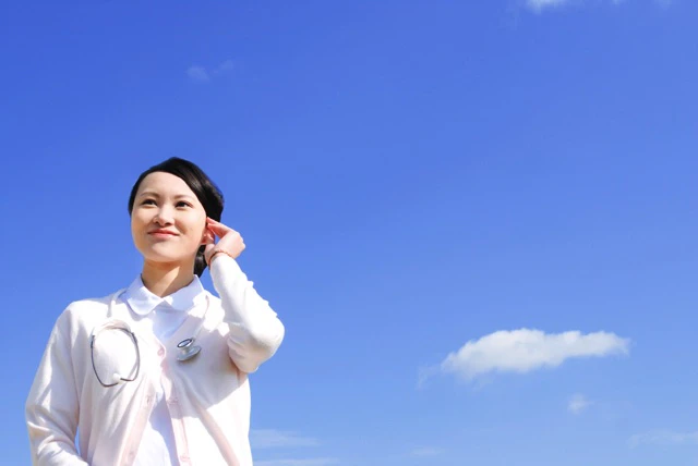 青空をバックに立っている看護師