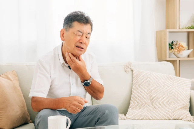 のどをおさえる男性