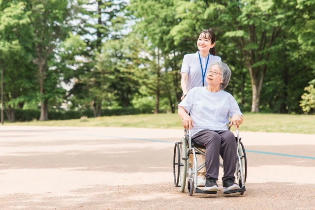 散歩する車いすの女性と療法士さん