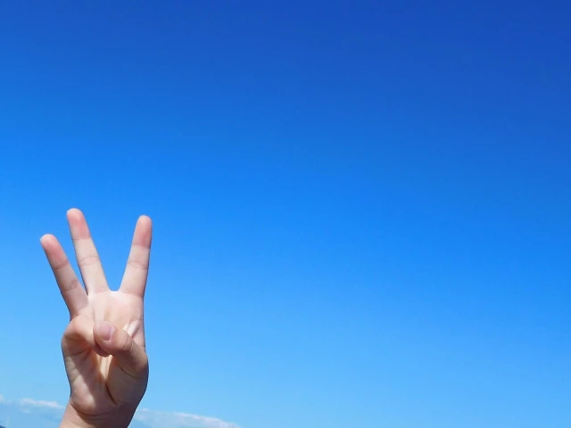 青空と三本指のポーズの手
