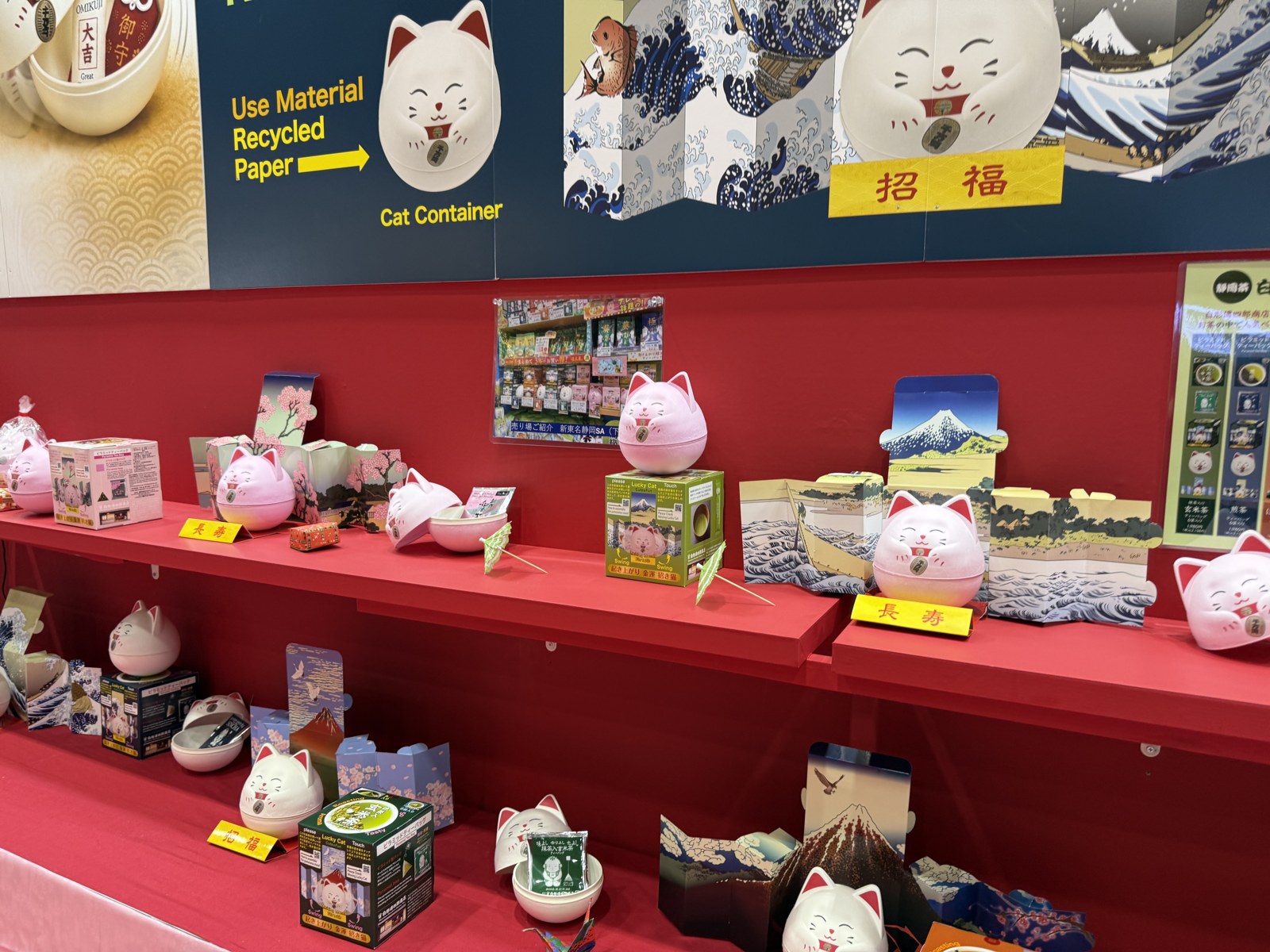 招き猫の形の容器と、桜・富士山・波を描いたパッケージ。商品と箱を組み合わせてお土産らしさを伝えています。