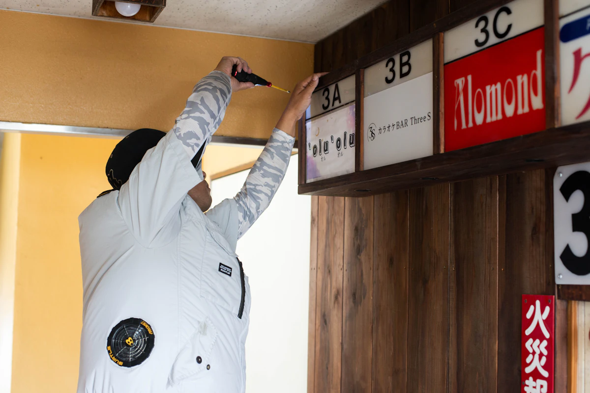 パートナーがThreeSのフロア案内看板を3Bの木製看板枠へ取り付けている様子。