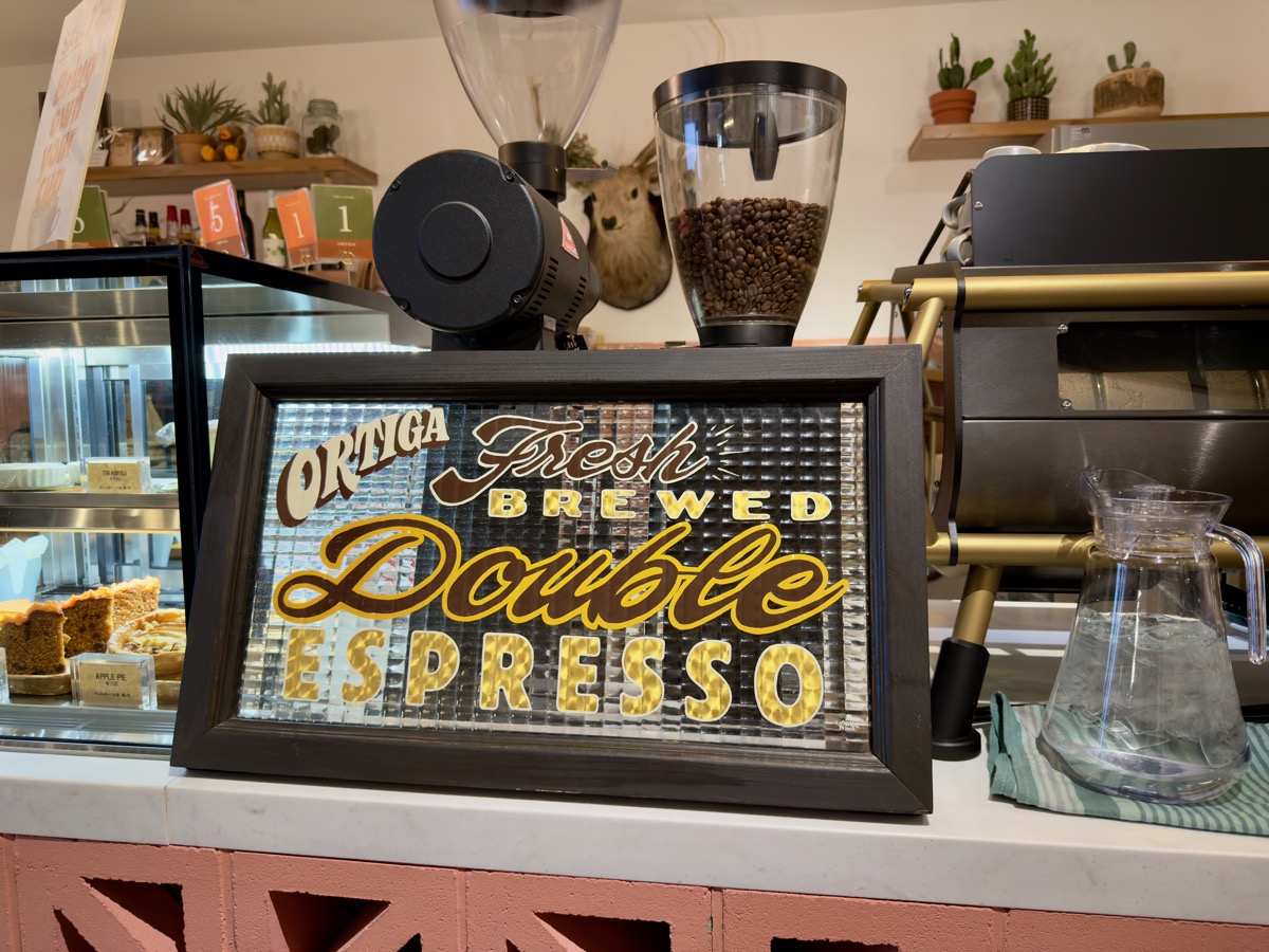 カウンター。エスプレッソマシンと「ORTIGA Fresh Brewed Double Espresso」のレタリングボード