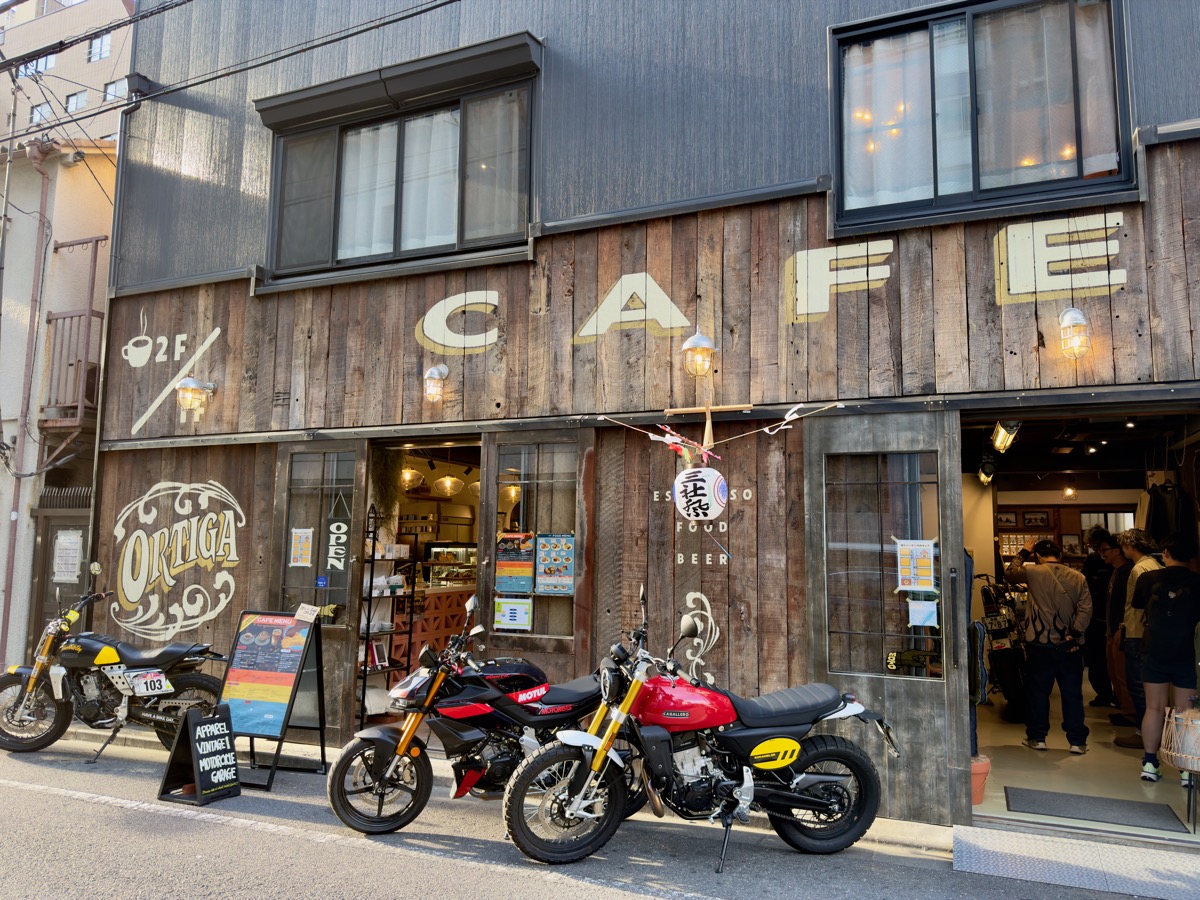 ORTIGAの外観。木目の壁にCAFEの文字、店先に試乗車が並ぶ
