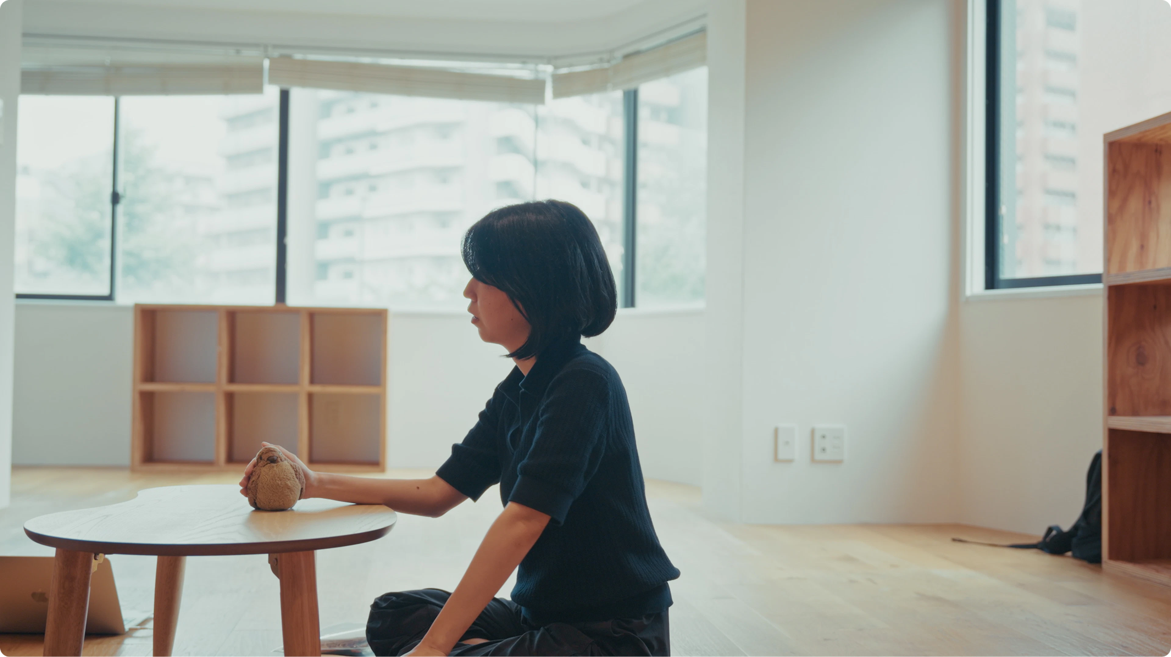 手に収まるサイズのトリのぬいぐるみを机の上で撫でる永井さん