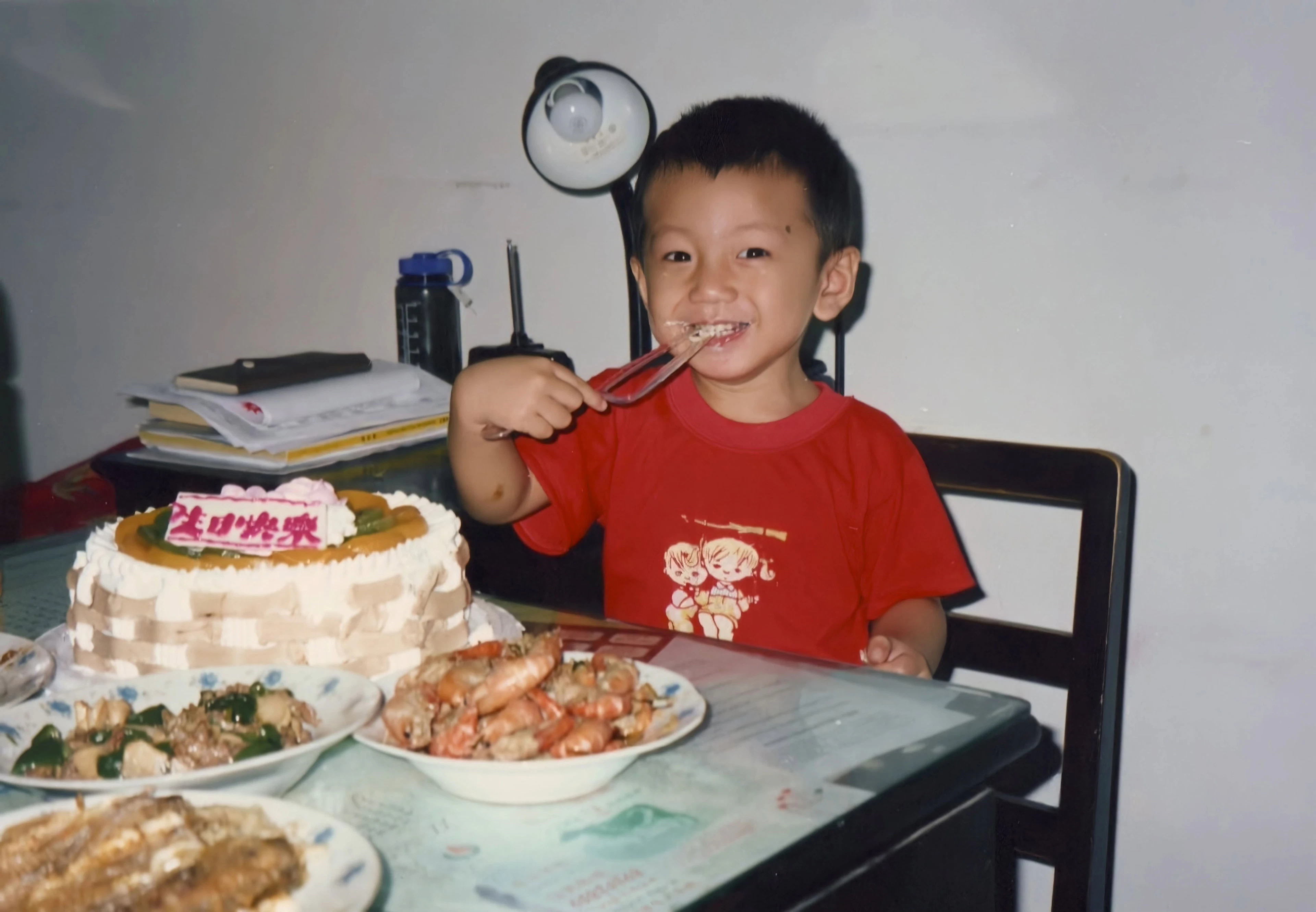 中国・上海で暮らしていたときのフーウェイさん。目の前には誕生日ケーキや、エビの料理が。