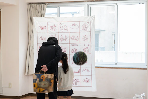 壁に掛けられた大きな布の作品を見る親子