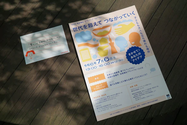木製のデッキに置かれたフォーラムのチラシと案内カード