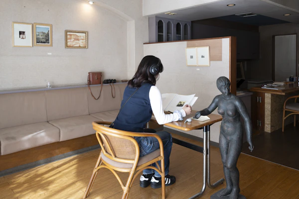 喫茶店の一角で、彫刻作品と向かい合って座る来場者