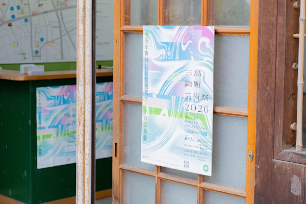 商店の入口に貼られた「三島満願芸術祭2026」のポスター