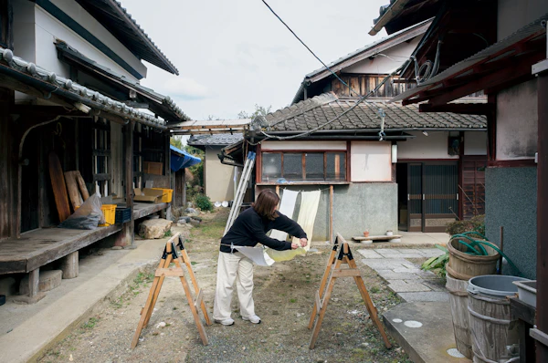 民家の庭先で作業台に向かう制作者
