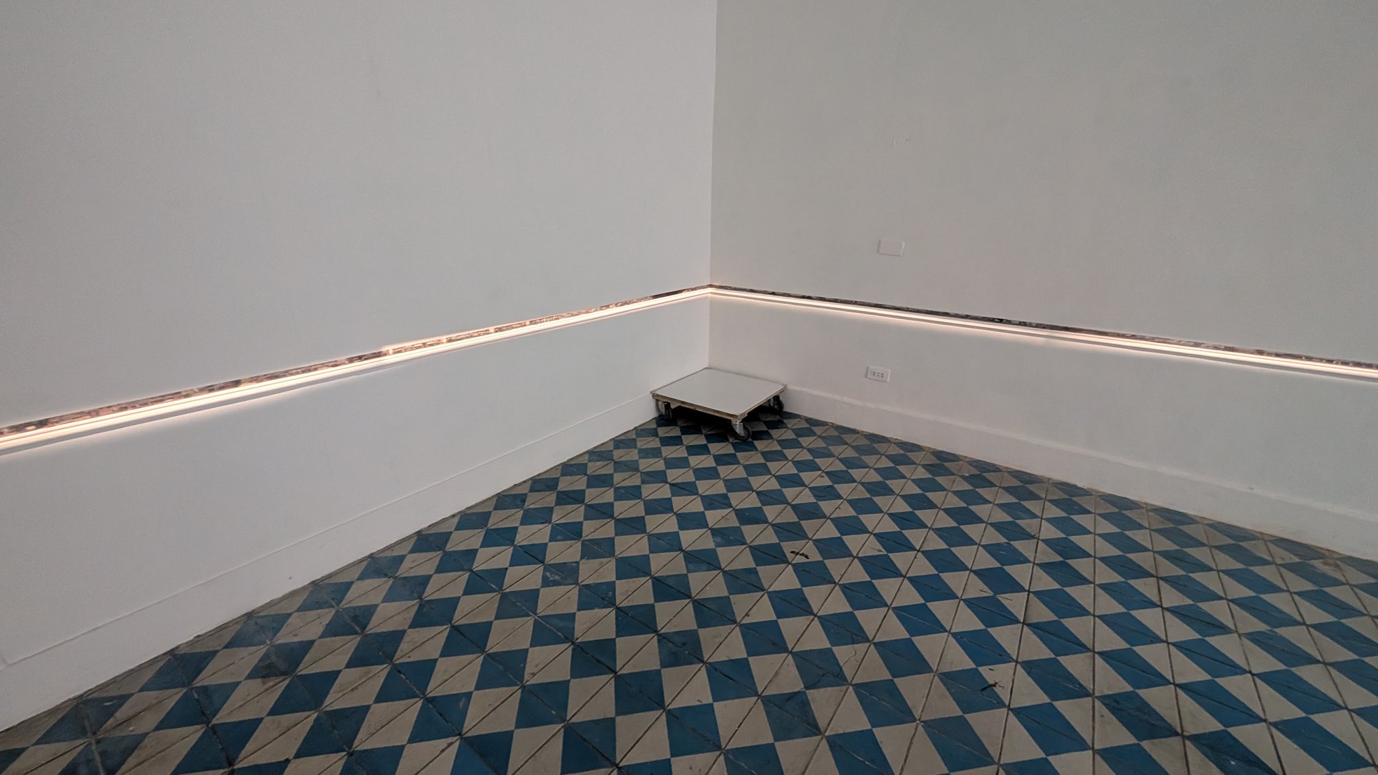 Ausstellungsansicht von „界行者“ bei 未命名. Das Licht entlang der Wand zeichnet eine weitere Kontur in den Raum.