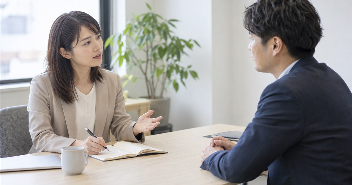 会議室でノートを開き、制作の担当者に質問するマーケティング担当者