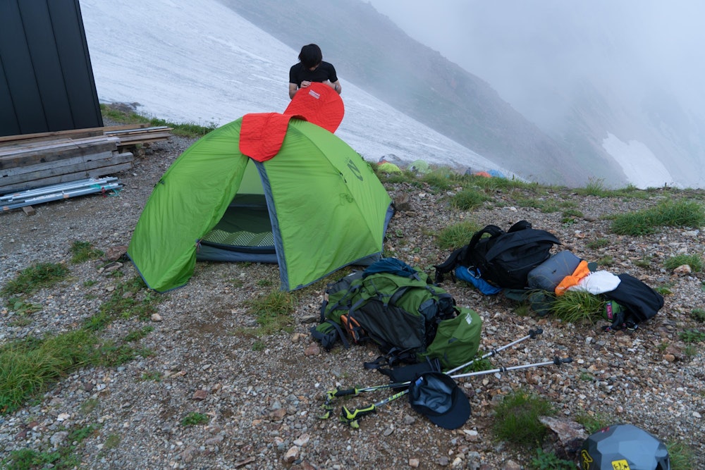 <p>結局晴れたのは一瞬だった。<br>天狗山荘のテント場に着いて設営準備をしていると雨が降ってきた。<br>明日も天気が悪い予報になっている。設営と撤収の時短のため、ひとつのテントに 2 人で寝ることにした。</p>