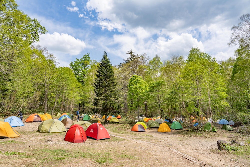<p>見晴にある唯一のキャンプ場に到着。<br>時刻は 13 時、スタートがゆっくりだったので、すでに多くのハイカーがテントを張っていた。<br>うまくスペースを見つけて設営する。</p>