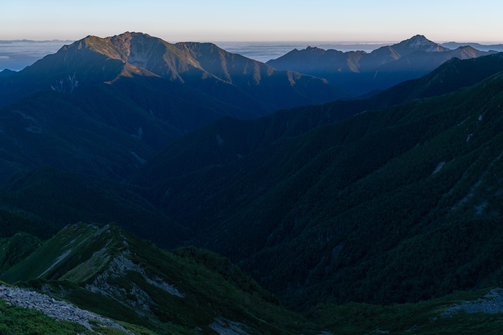 <p>初日の夜は両俣小屋でテント泊。<br>この日は一気に塩見岳を目指すため、3 時ごろ出発し、稜線で夜明けを迎える。<br>振り返ると朝日に染まる仙丈ヶ岳が見えた。</p>