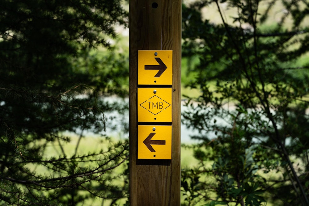<p>TMB（Tour du Mont Blanc）のルートであることを示す表示。<br>真ん中のプレートが外されて、矢印だけになっているところもあった。</p>
