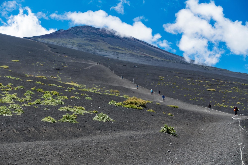 <p>御殿場口まで戻ってきた。<br>入山時は夜間でわからなかったが、こんな感じで富士山が見えていたのか。<br>山自体が大きいのに地形が単純なので、山頂まで近いのか遠いのか分からない。<br>人生 2 回目の富士登山は、御殿場口という主要 4 ルートの中でもっとも距離のあるルートで、たしかに体力的にも前回の須走ルートよりタフだった。<br>それでも、下山時の大砂走りの爽快感はすさまじく、これを楽しみに御殿場口を選んでもいいぐらいだと思う。</p>