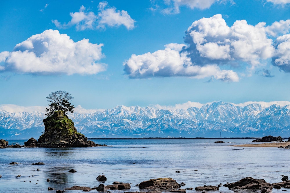 <p>富山県、雨晴海岸。<br>ふもとの方までたっぷりと雪を被った立山連峰が一望できる。<br>繰り返すが、冬の北陸だ。ふらっと観光で訪れた日にピンポイントでここまで穏やかな天気に恵まれるのは奇跡に近い。</p>
