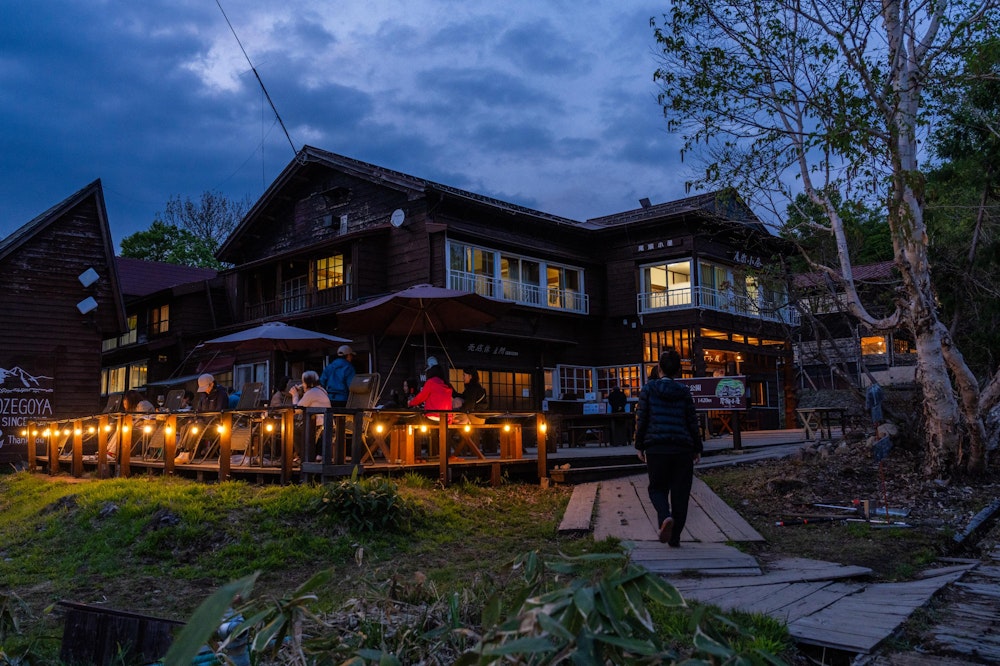 <p>夜が近い尾瀬小屋で、それぞれの時間を過ごす宿泊者たち。<br>このテラスは尾瀬小屋に泊まっている人もテント泊の人も自由に使うことができる。</p>