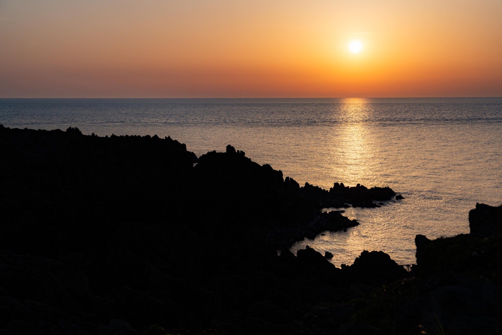 <p>雄島の岩場越しに、まもなく沈む夕陽を見送る。</p>
