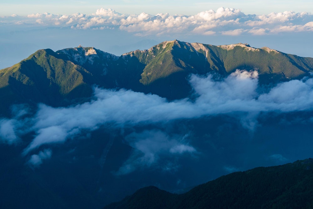 <p>日没間際の鳳凰三山。稜線のわずかな部分だけが白い岩肌が露出している。<br>地蔵ヶ岳のオベリスクも見える。</p>