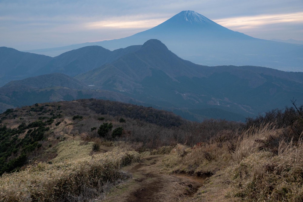 <p>明神ヶ岳をすぎ、再び大きな富士山が視界に入るように。雲も出て、薄暗くなってきた。<br>日没を少し過ぎて、暗くなった頃に無事に入山地点について、周回ルートが完成した。<br>50km の道のりは想像以上にタフだったが、箱根のすべてを 1 日で満喫することができた。</p>