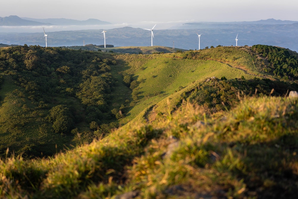 <p>遠くに風力発電施設が並ぶ。<br>さらに奥には、雲海が広がる阿蘇カルデラが見える。</p>